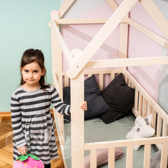 A girl standing next to a Montessori house bed 