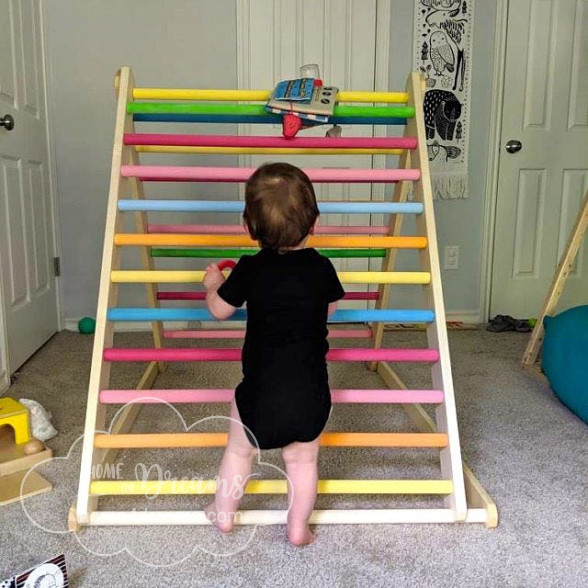 A baby climbing on a customizable wooden climbing frame 