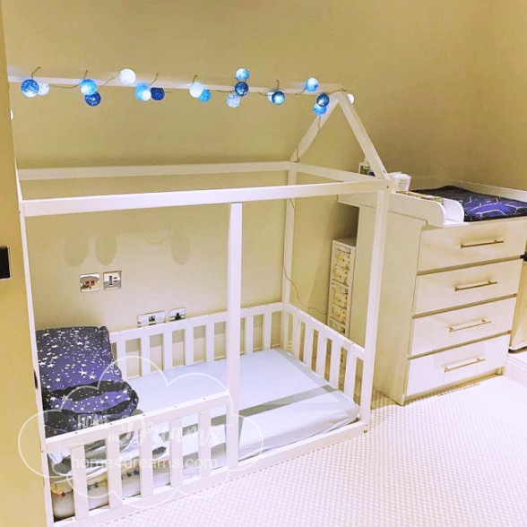 A toddler bed with rails, decorated with a lighting chain.