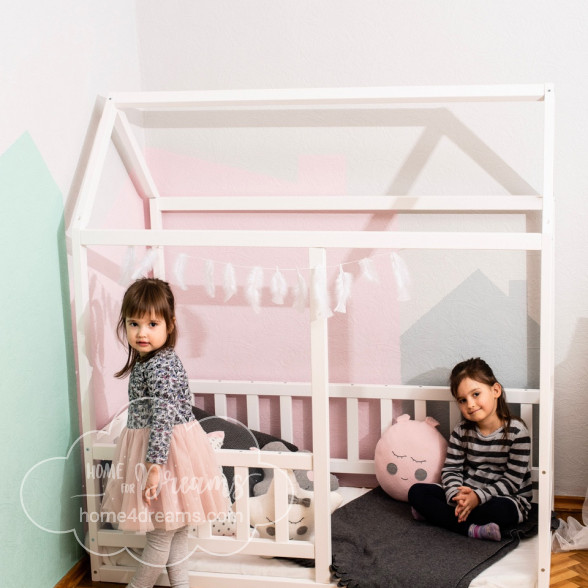 Children playing next to a wooden toddler bed