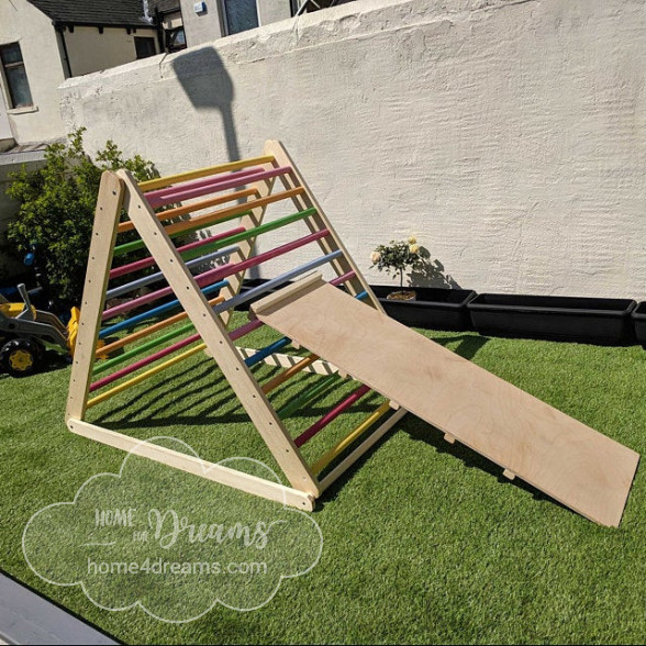 A rainbow-colored wooden climbing frame placed in a garden