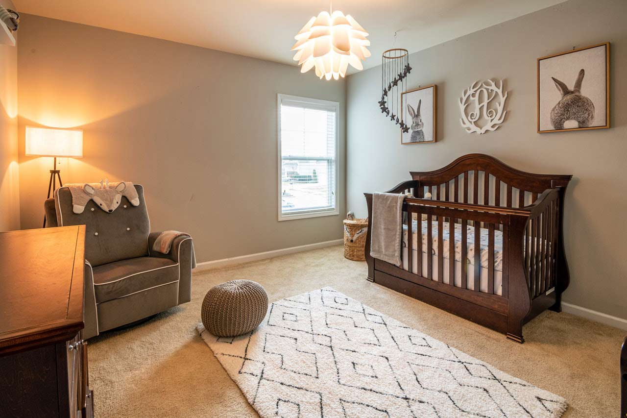 A baby nursery with a wooden crib, armchair and various other furniture and décor